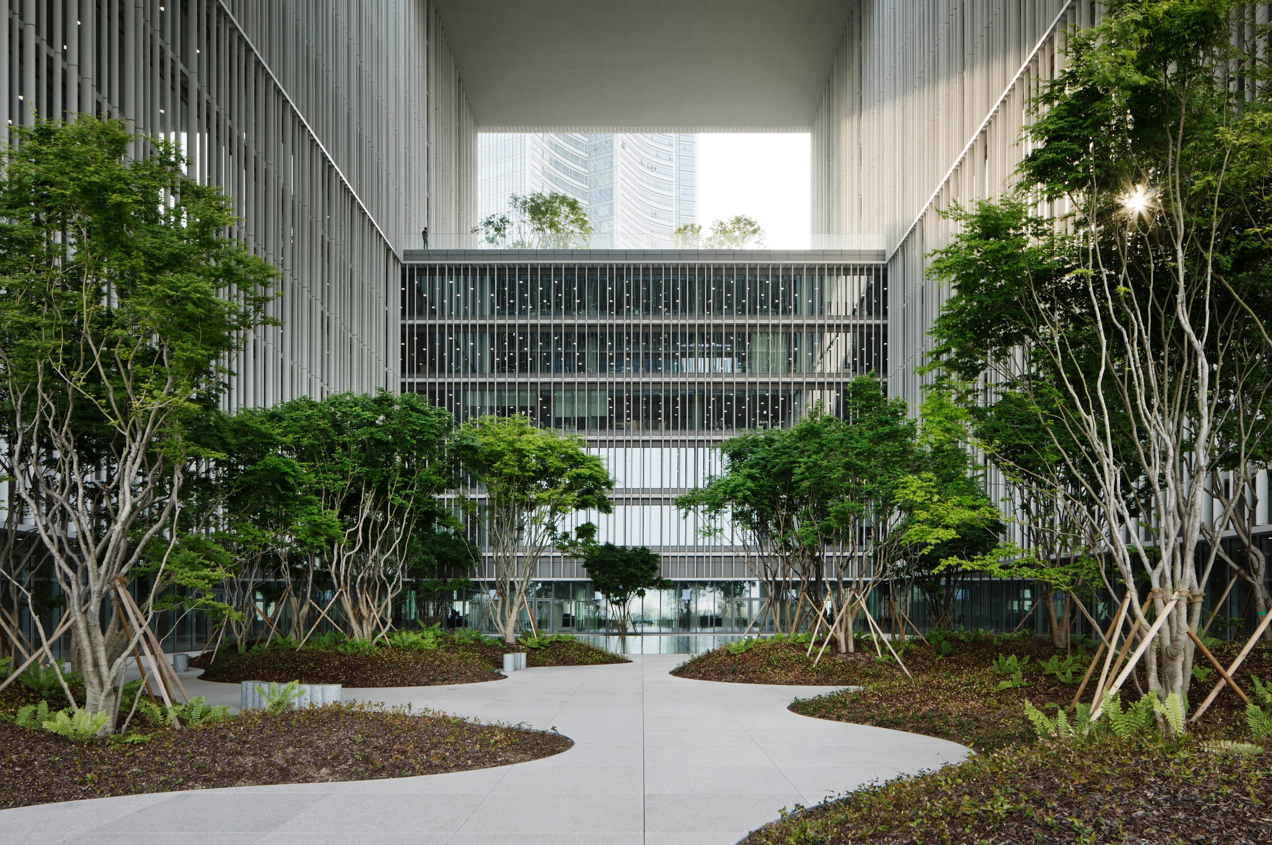 Central courtyard garden with trees, stone paths, and aluminium-finned walls at Amorepacific Headquarters, Yongsan, Seoul