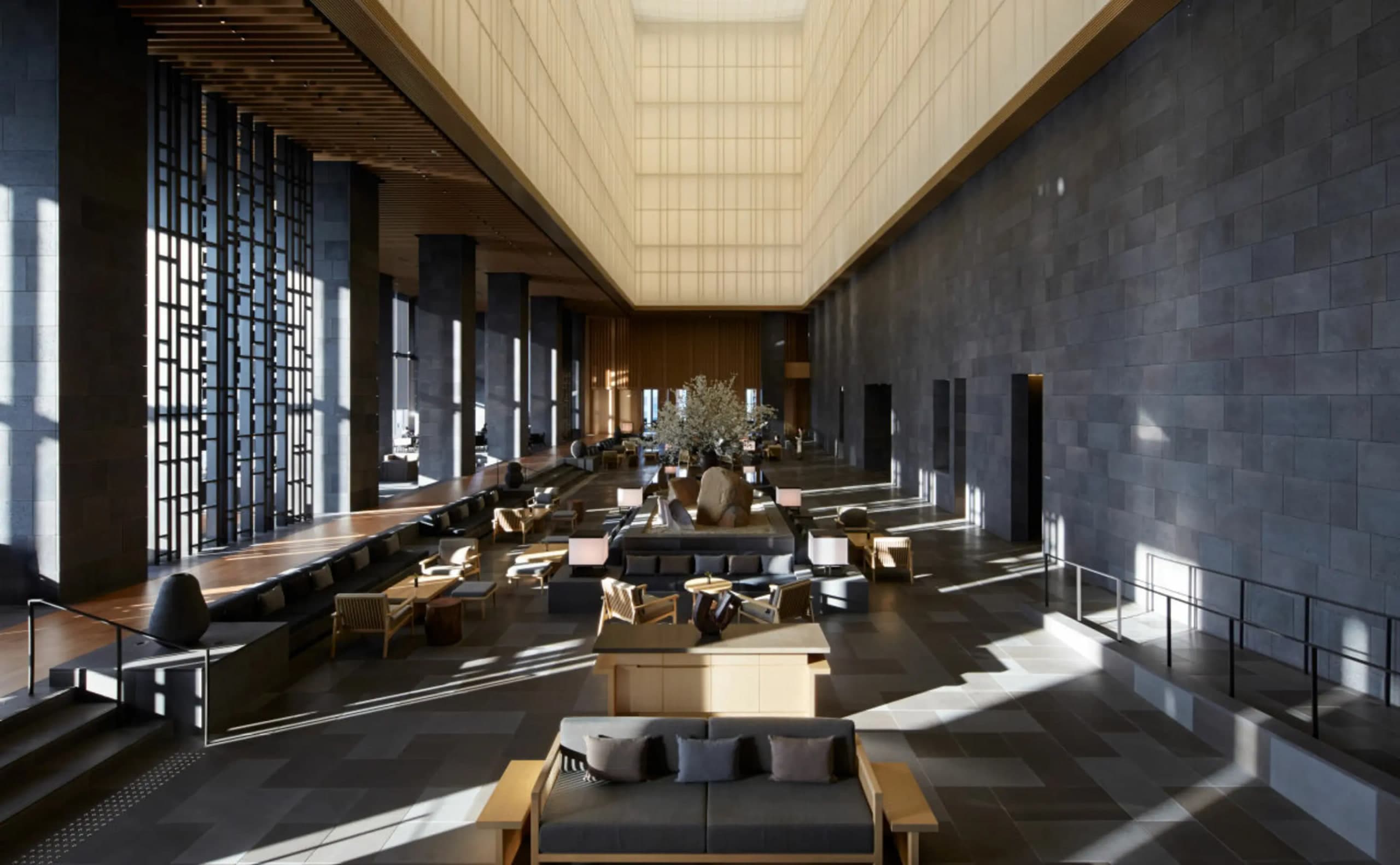Aman Tokyo 33rd-floor lobby with soaring washi-paper lantern atrium, dark stone floor, and low lounge seating
