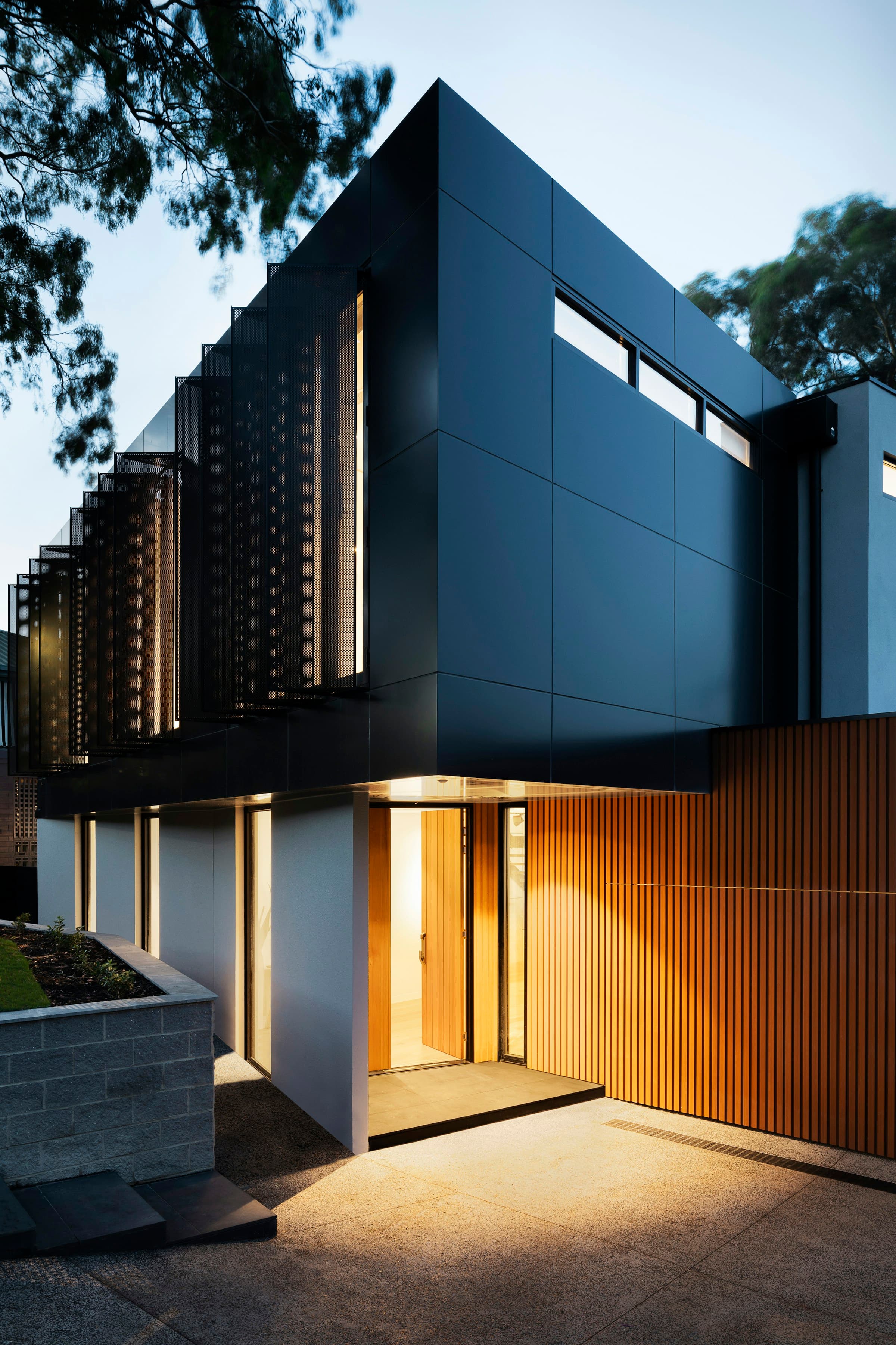 Modern residence entrance with stone paving and layered landscaping