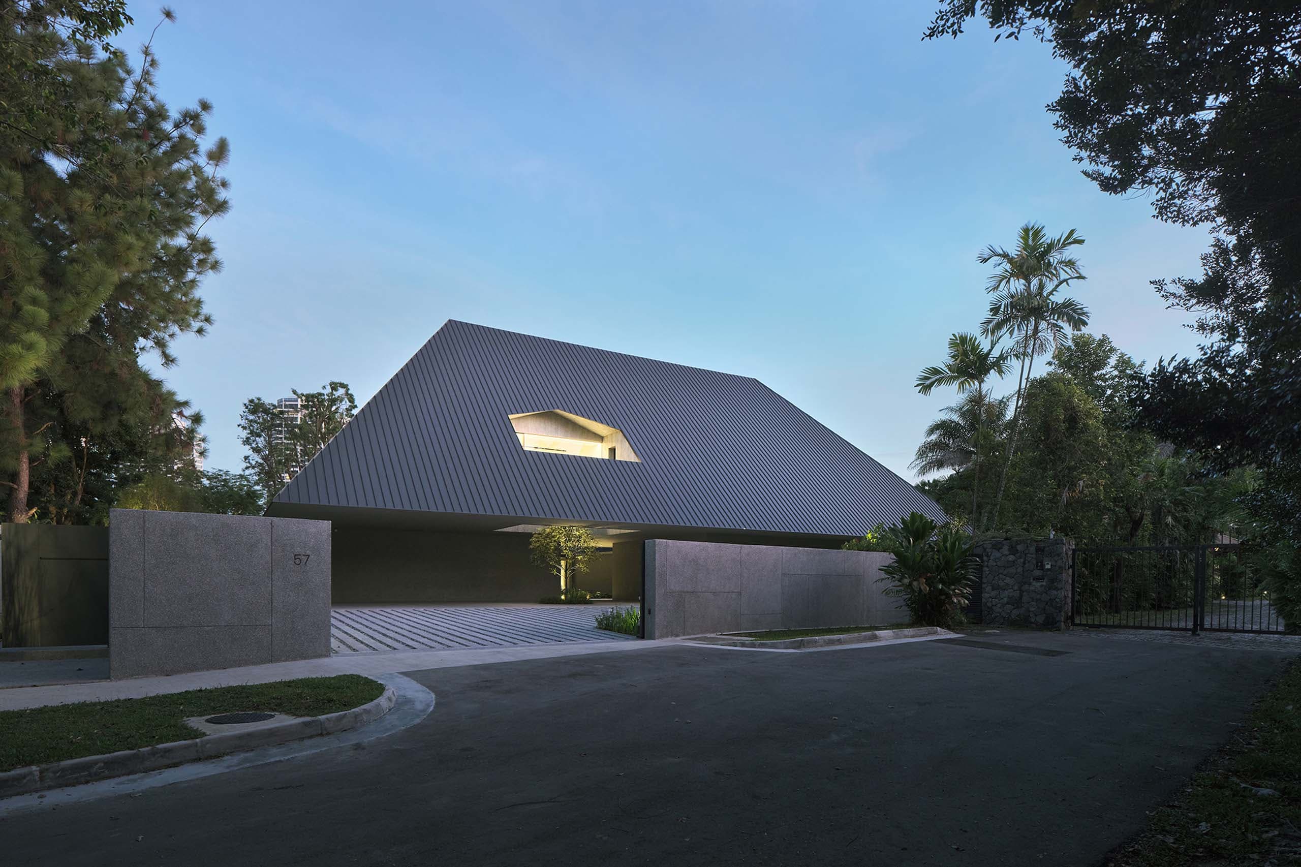 House of Remembrance in Singapore at dusk: a grey hipped roof with a small window glowing above a granite gate