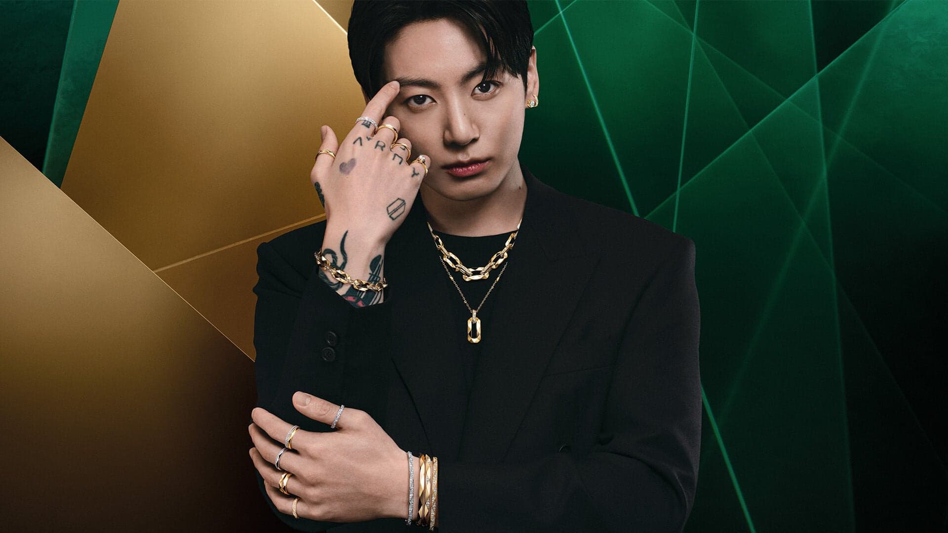 Jung Kook wearing layered Laurence Graff Signature yellow gold and diamond jewelry against Graff green and gold geometry