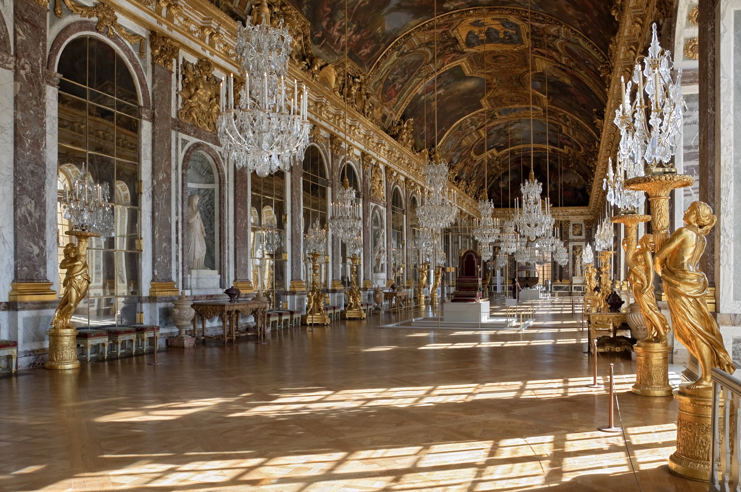 Looking the length of the Hall of Mirrors at the Palace of Versailles, with mirrored arches facing garden windows