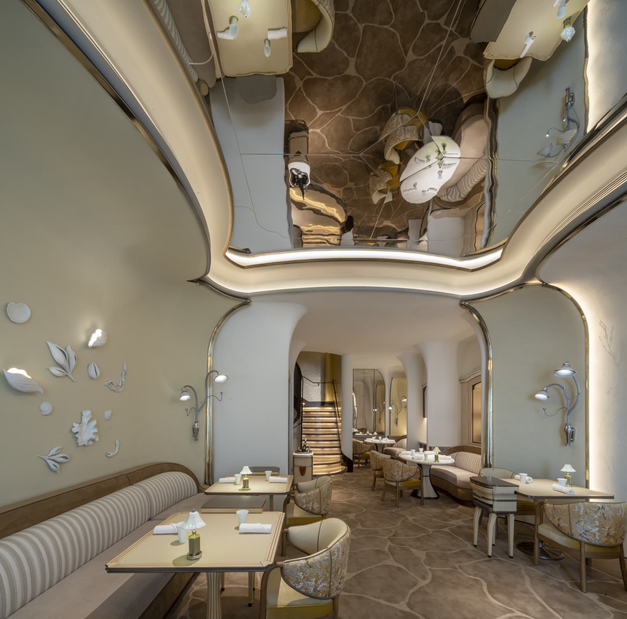 Curved cream dining room at Tate on Lok Ku Road with striped banquette, floral chairs, and mirrored ceiling