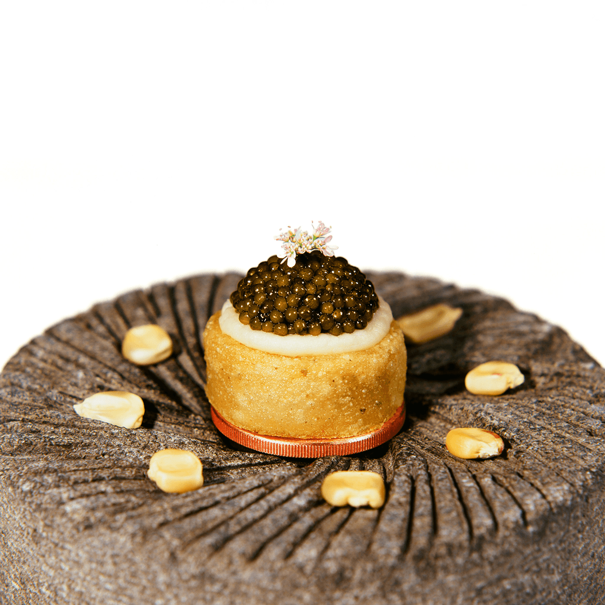 A sope topped with white cream and caviar on a stone masa grinder at Californios in San Francisco