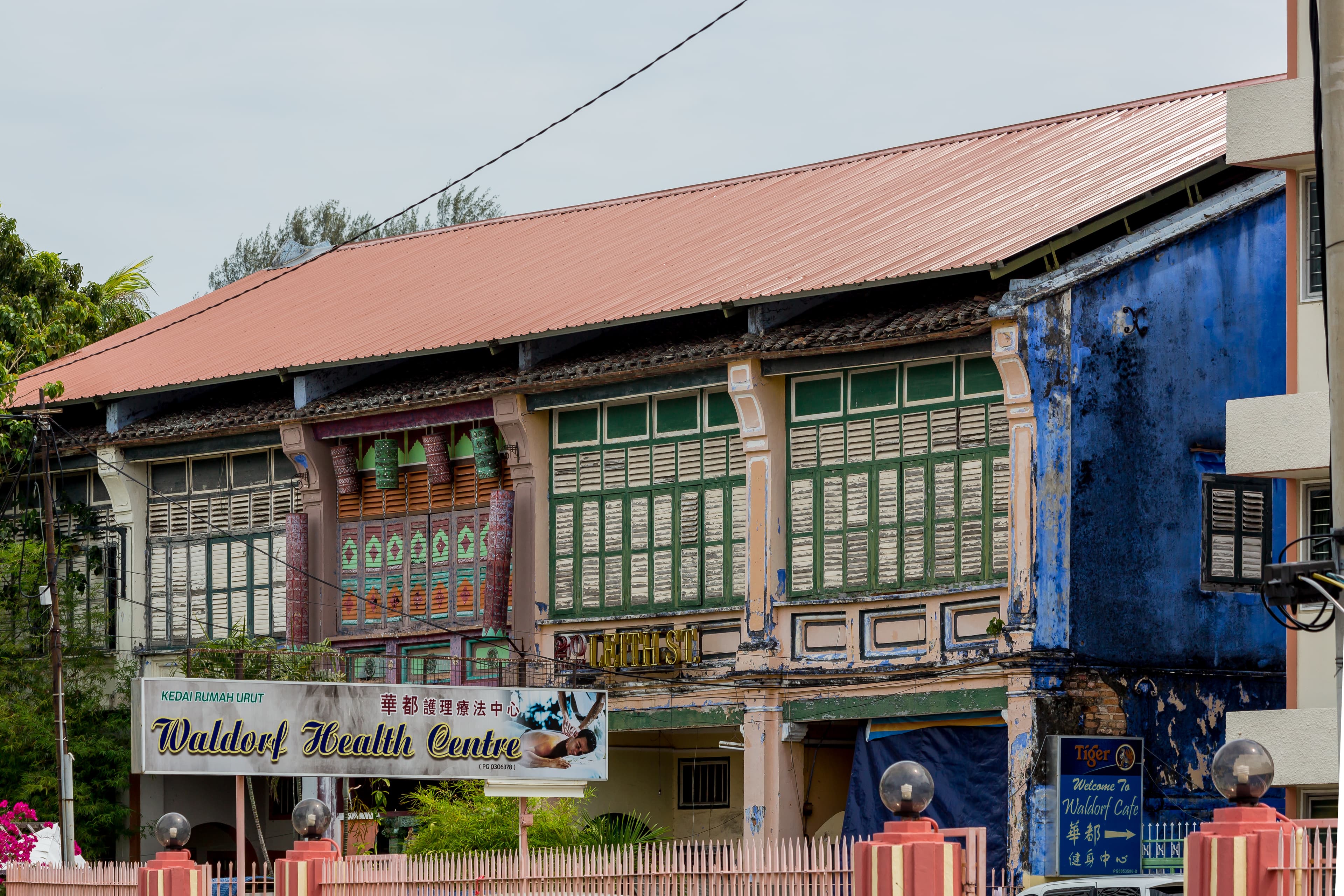 George Town row-house façade on Leith Street with colorful timber shutters and ground-floor shop signs