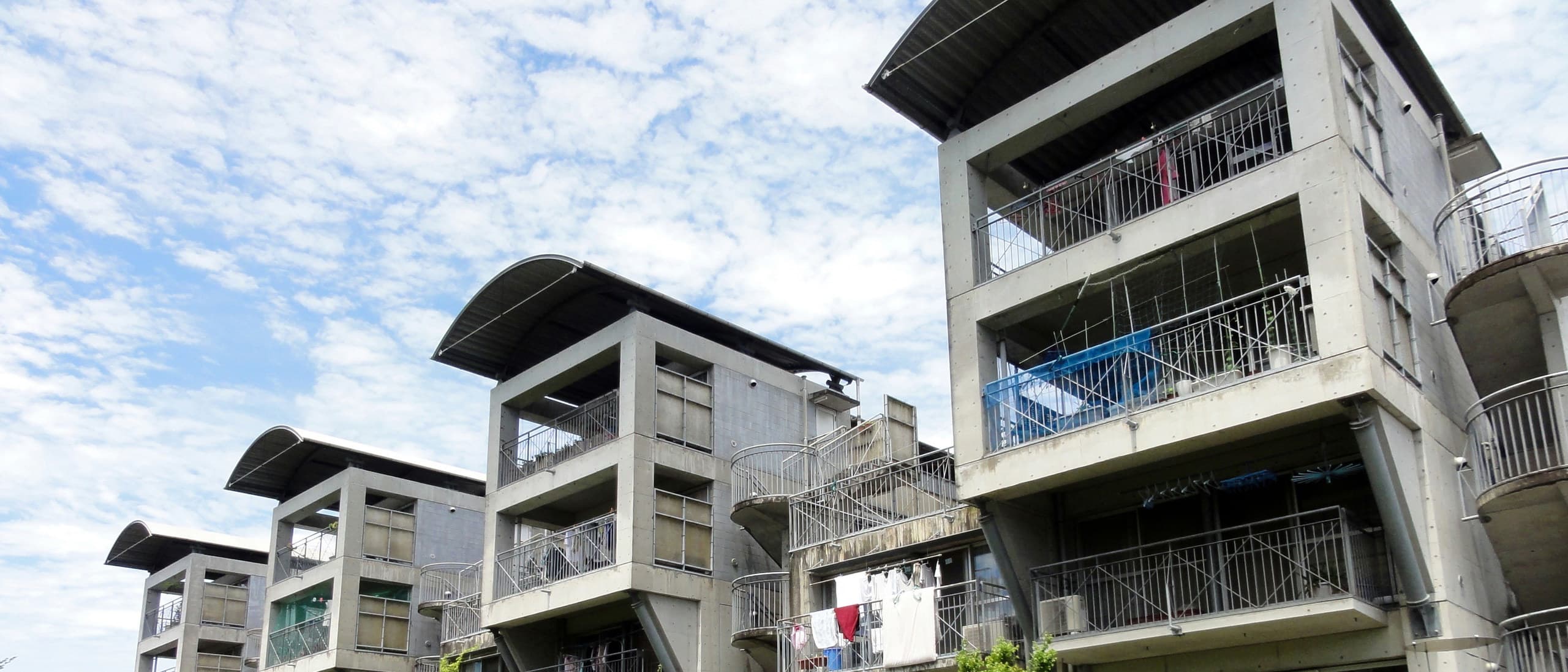 Hotakubo Daiichi public housing courtyard-facing elevation with vaulted balcony roofs and laundry, Kumamoto