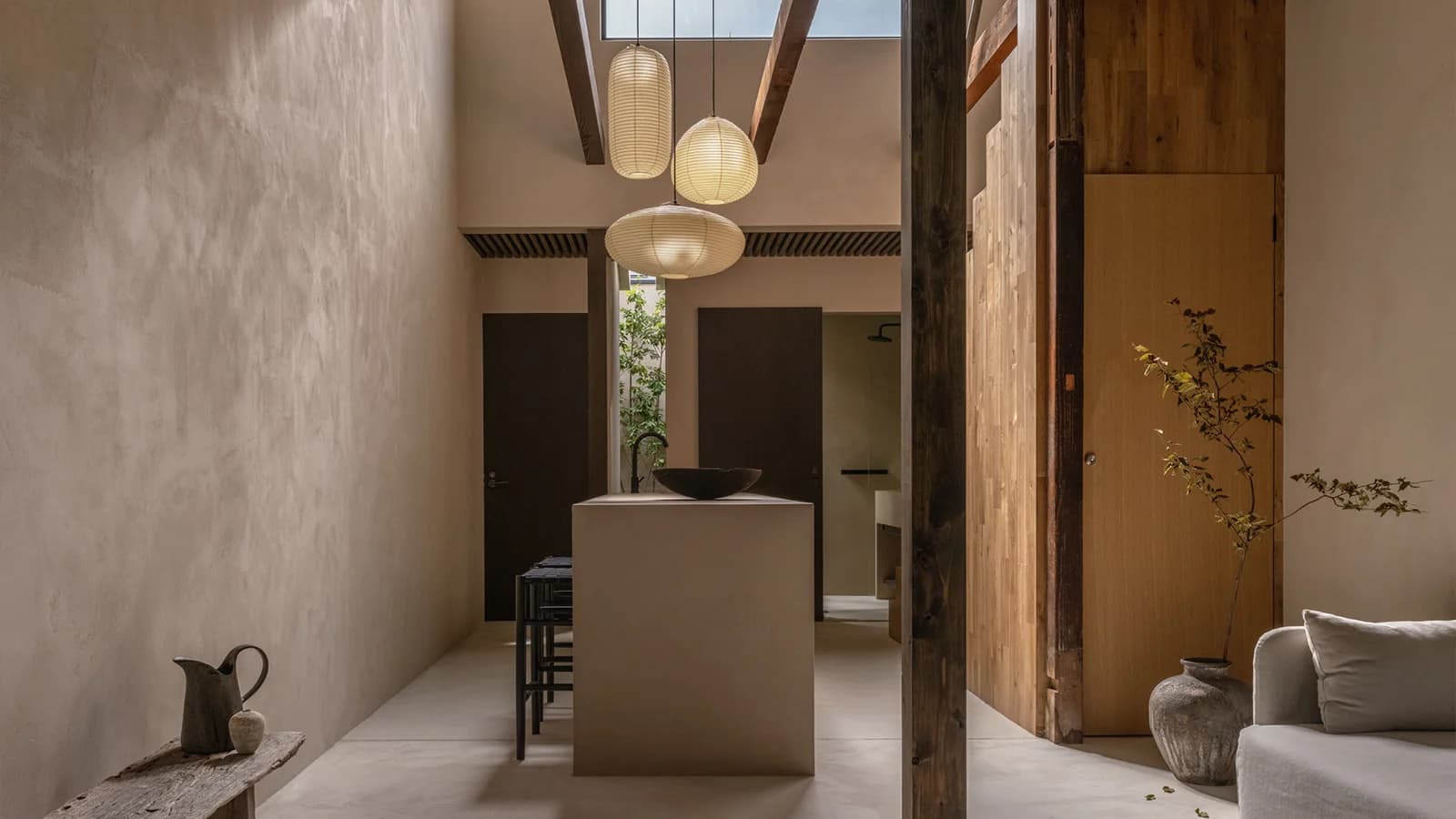 Open-plan suite interior at Maana Kiyomizu with plaster walls, washi lanterns, and a glimpse of inner courtyard greenery