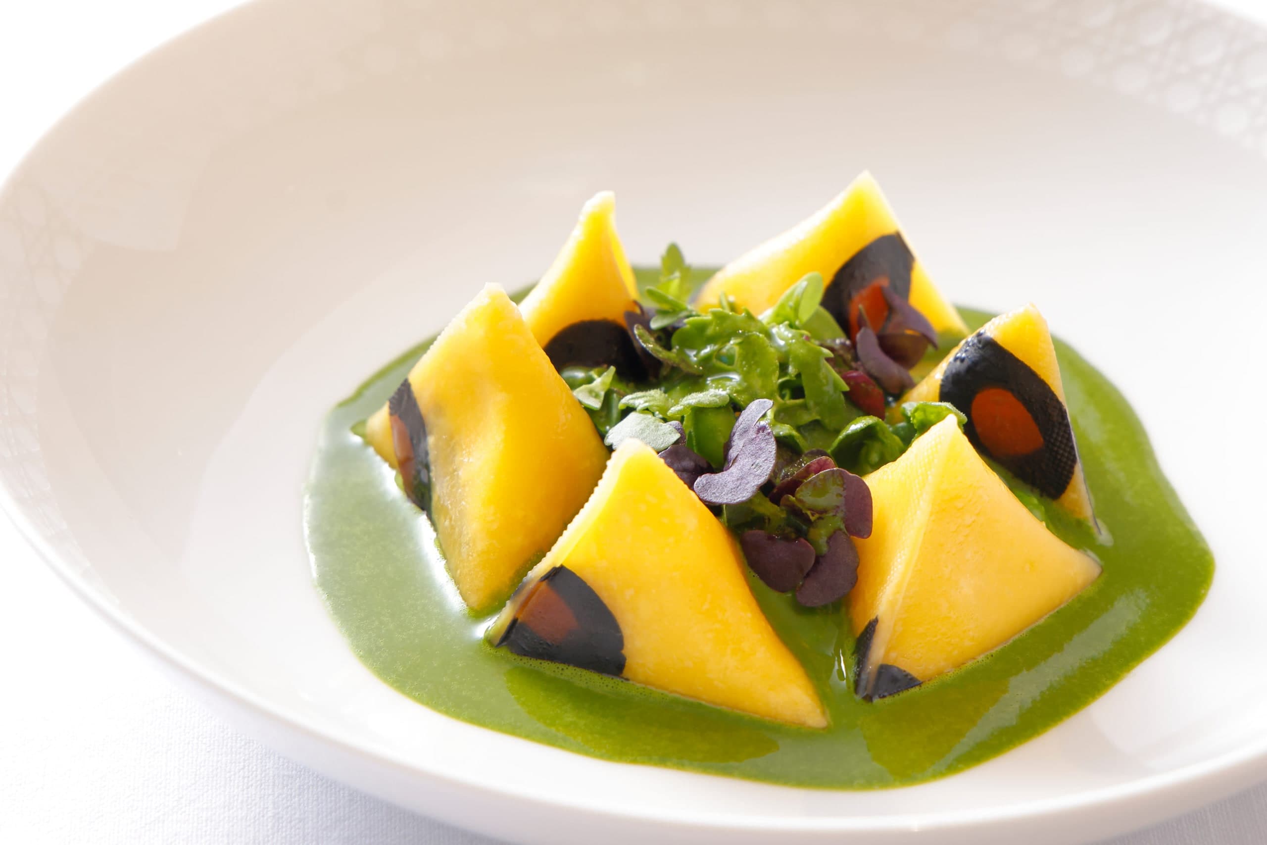 Les Berlingots Leopard: yellow pyramid pasta with dark leopard spots in a green pea sauce