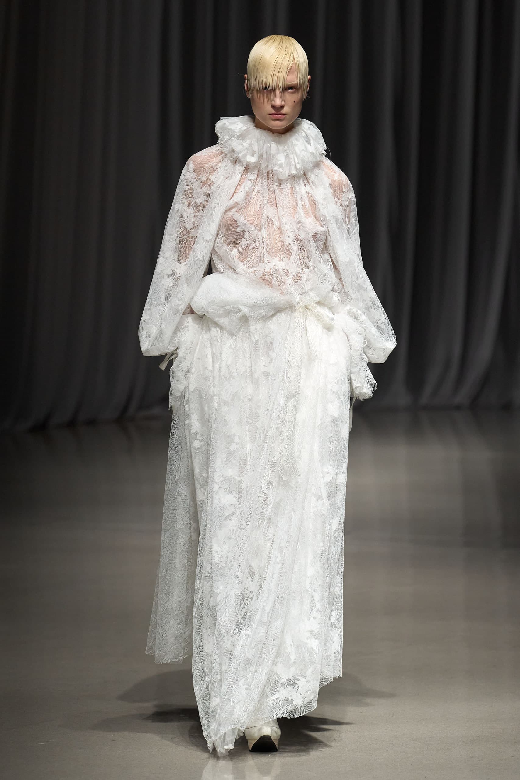 Model in sheer white floral lace with a ruffled collar and balloon sleeves, Mukcyen Fall 2026 at Rakuten Fashion Week Tokyo