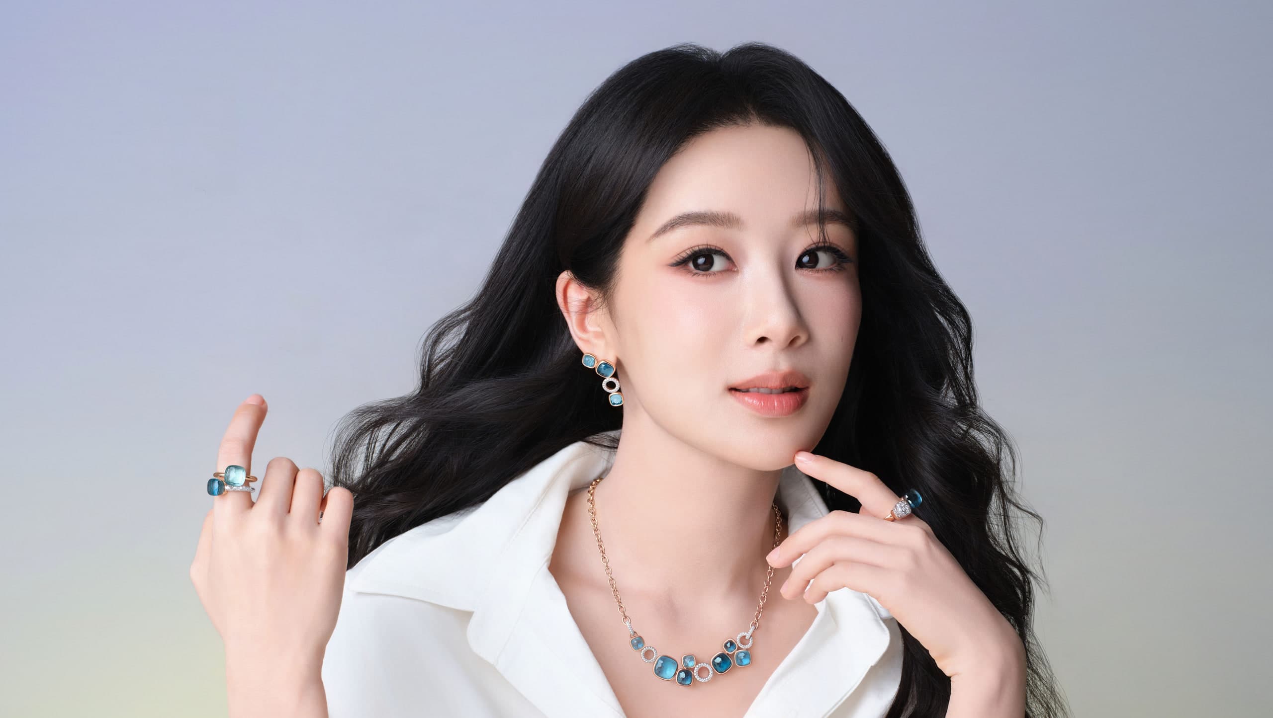 Yang Zi wearing stacked Pomellato Nudo rings, earrings, and necklace in rose gold with blue topaz and diamond pavé