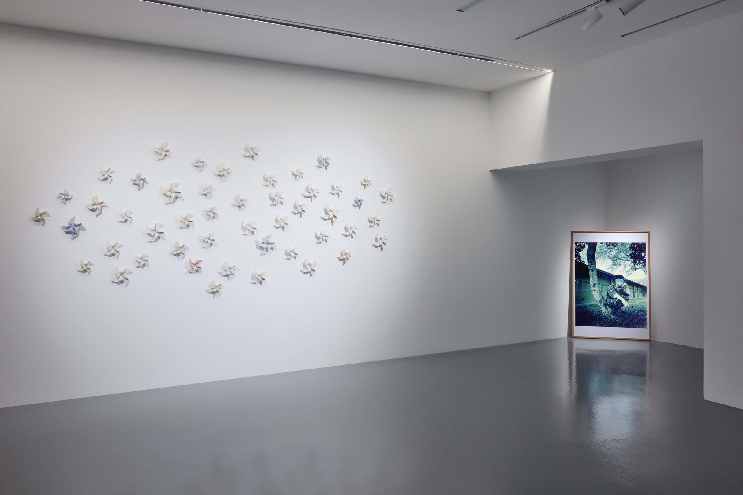 Shane Ng porcelain pinwheels on the main wall of FOST Gallery, with a framed photograph leaning in the alcove beyond