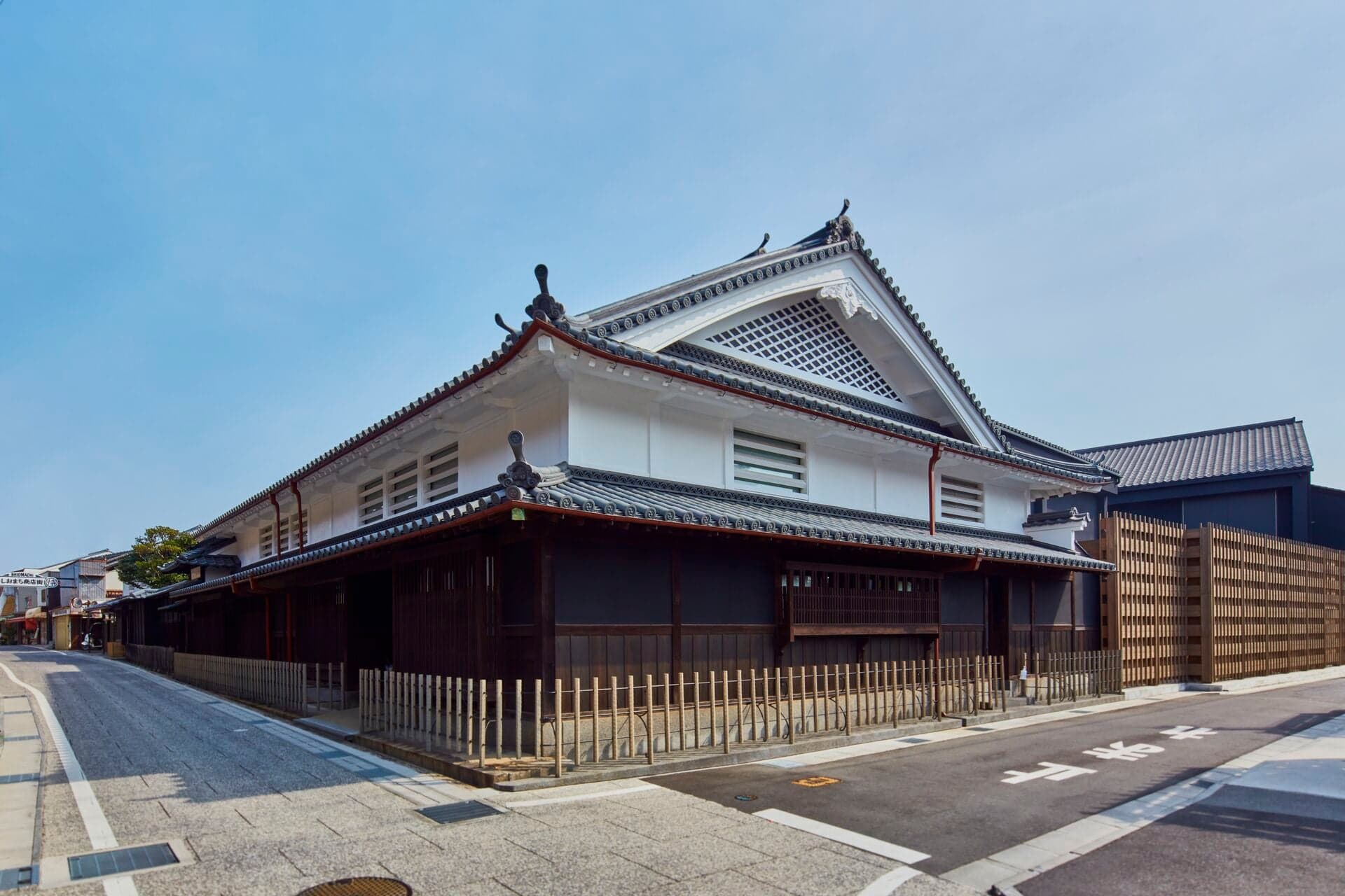 Street corner view of Azumi Setoda’s tiled roofs, white upper storey, and dark wooden lattice on Ikuchijima