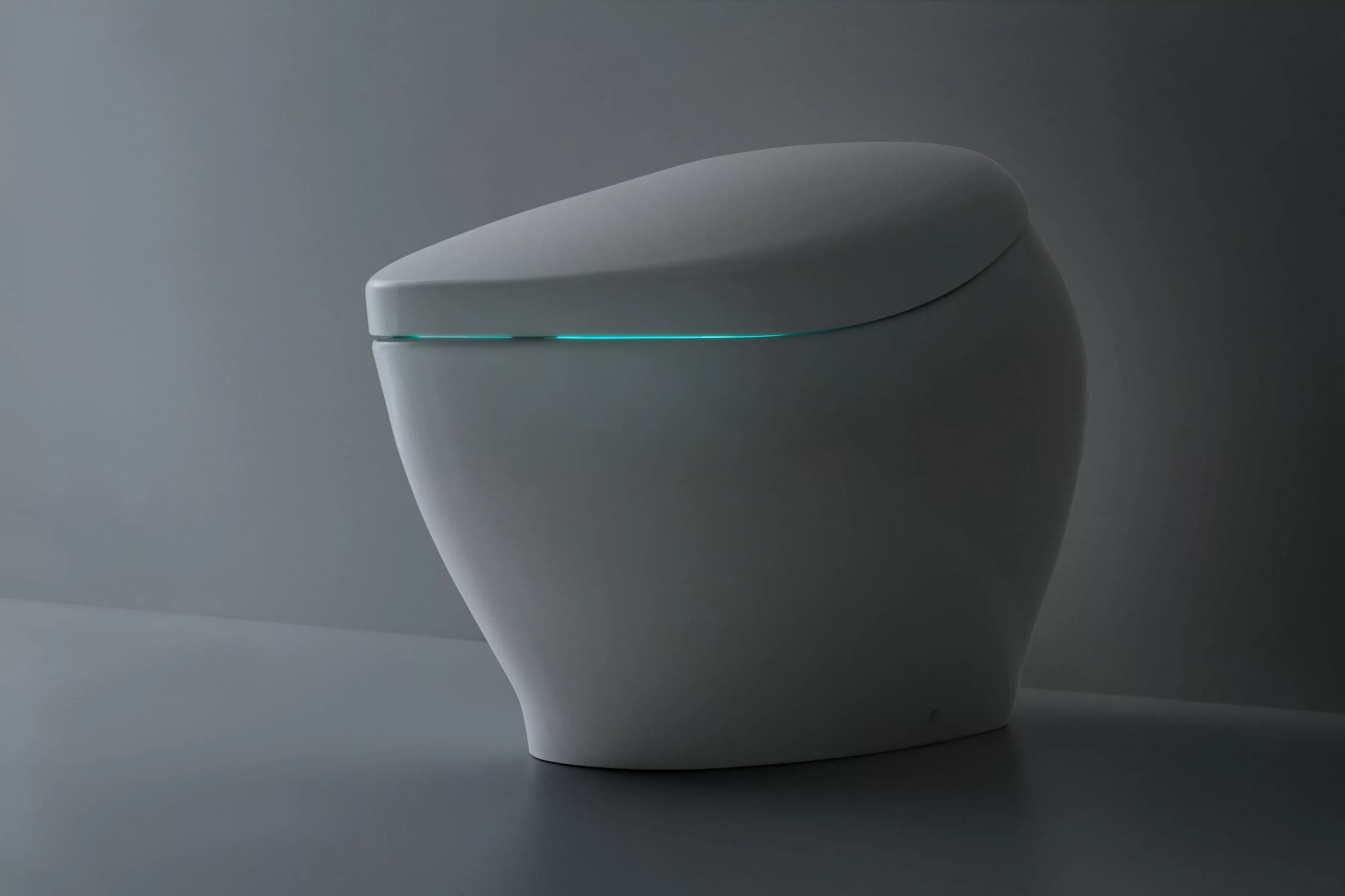 TOTO NEOREST NX2 integrated smart toilet with ACTILIGHT lid glow on a dark studio backdrop