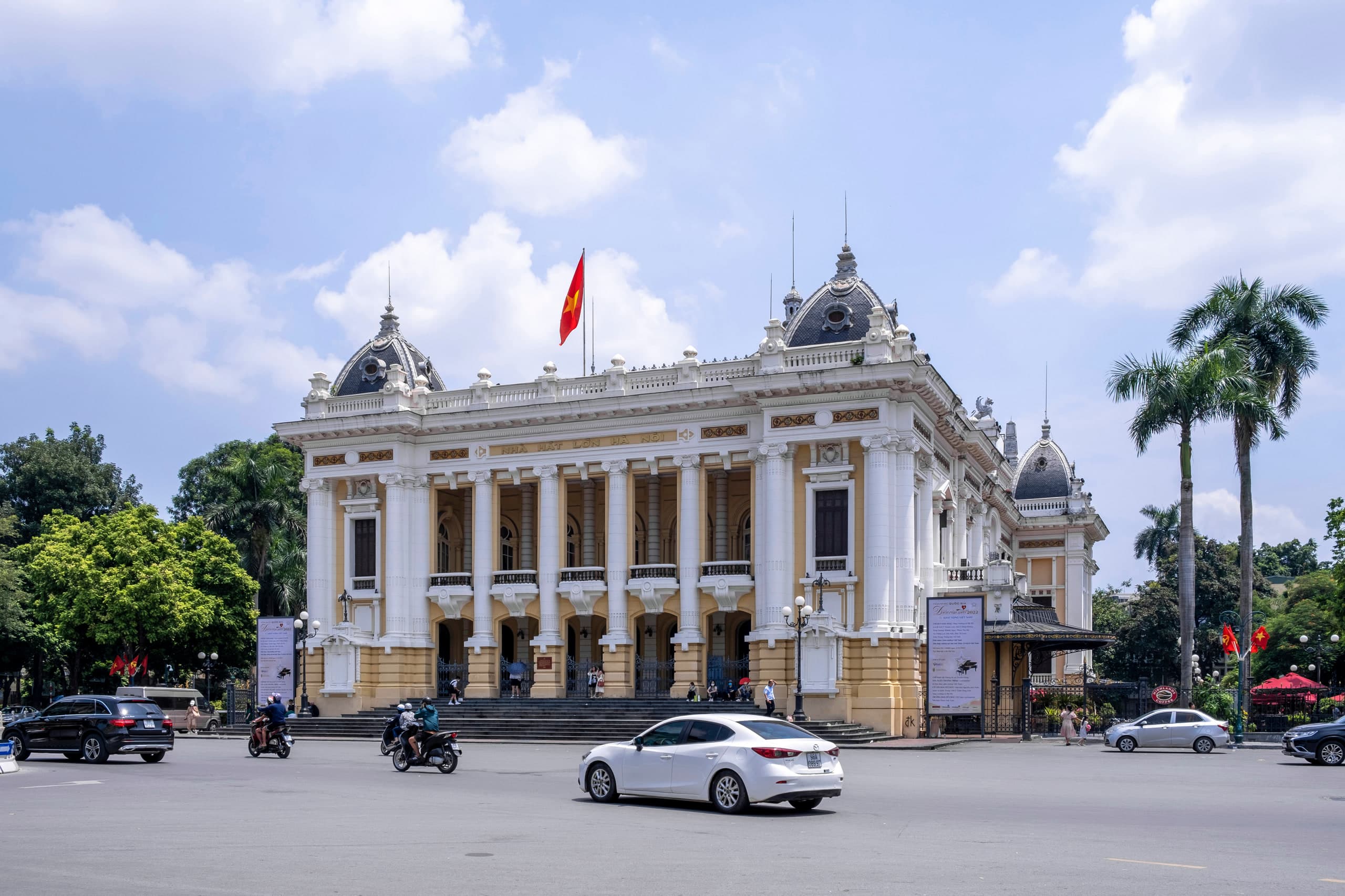 The Hanoi Opera House facade on Trang Tien, photographed in September 2022, with a Vietnamese flag above the columns