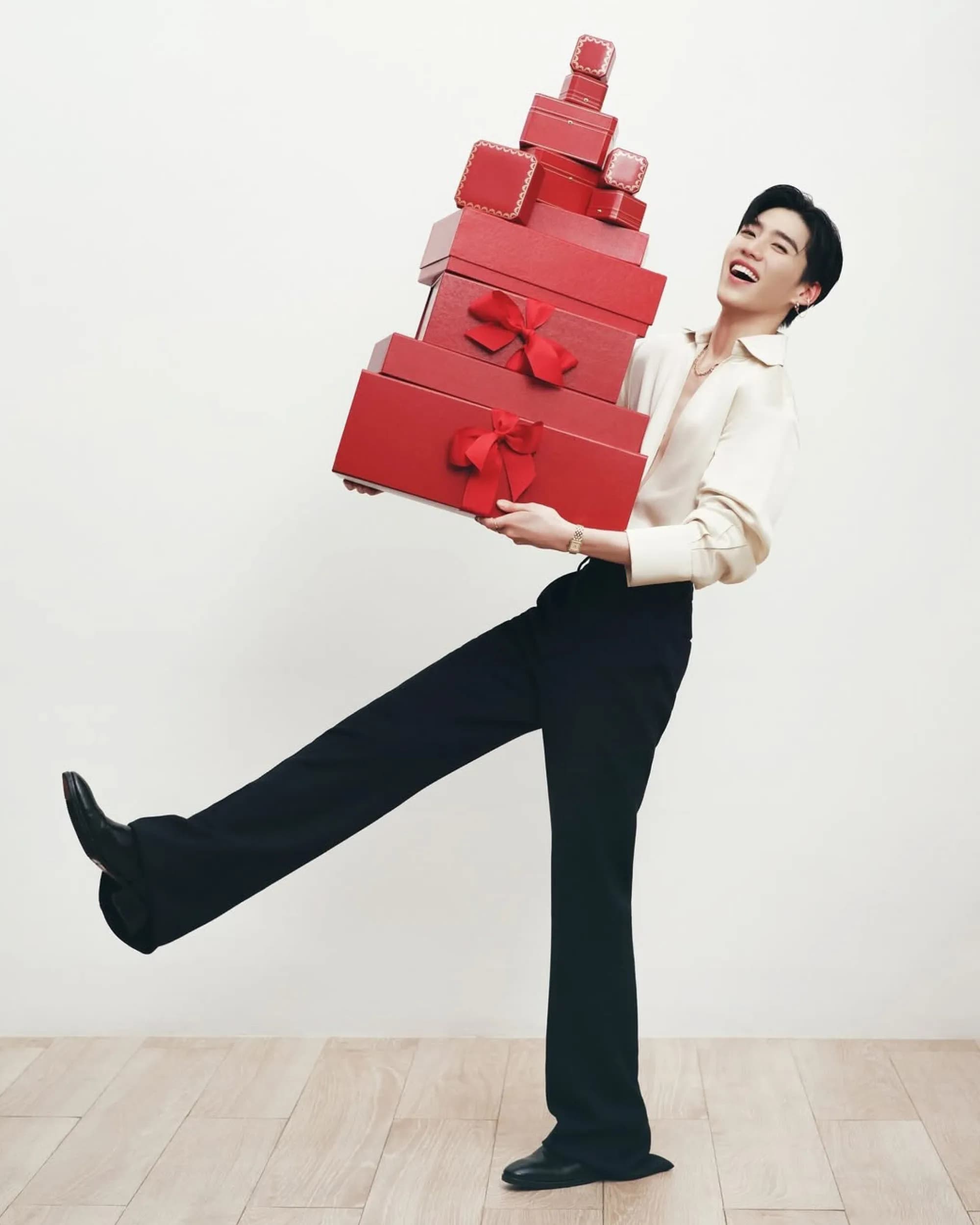 PP Krit Amnuaydechkorn balancing a tall stack of Cartier red gift boxes in a cream silk shirt and black trousers