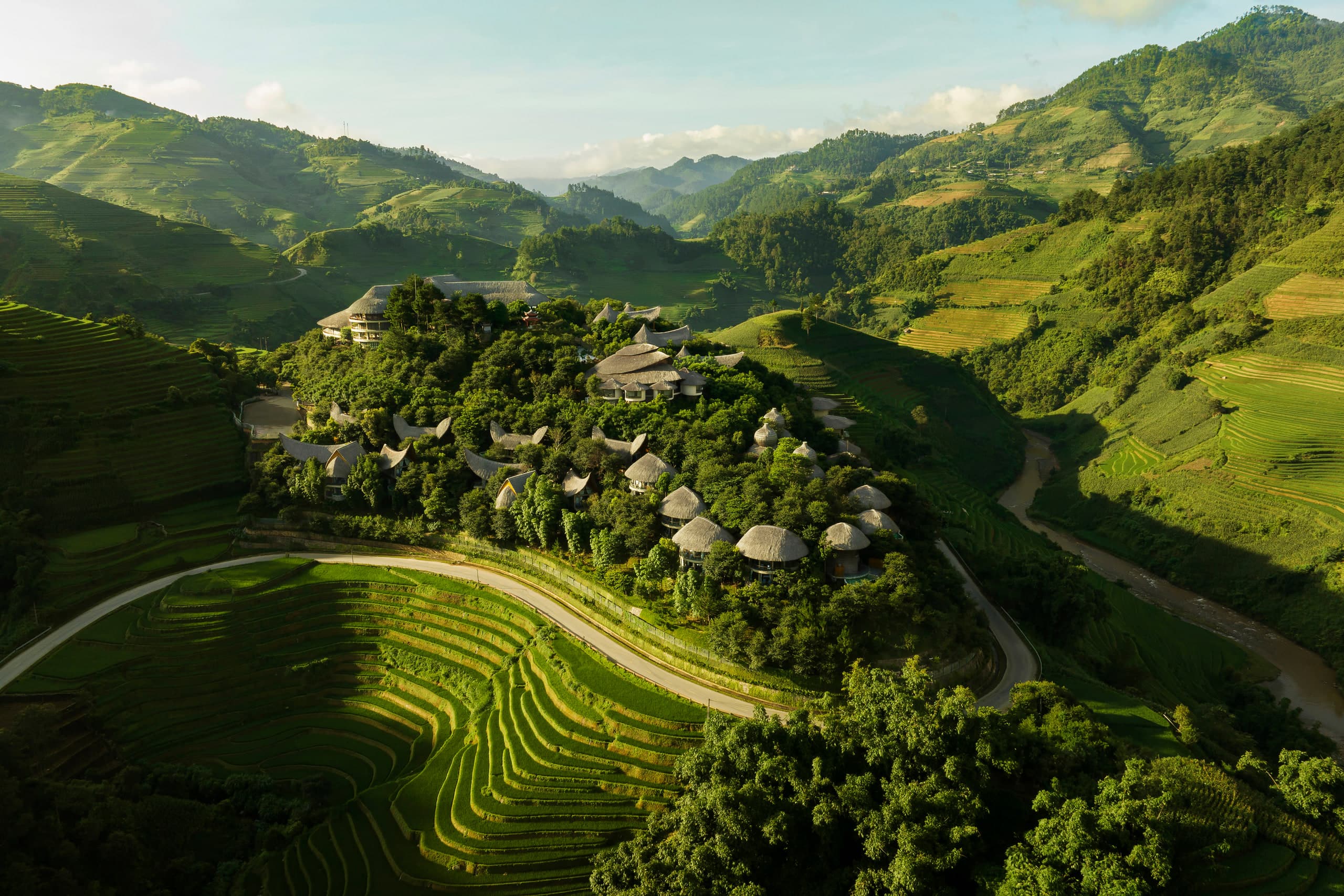 Aerial view of Garrya Mu Cang Chai thatched villas set into rice terraces and mountain forest in Yen Bai