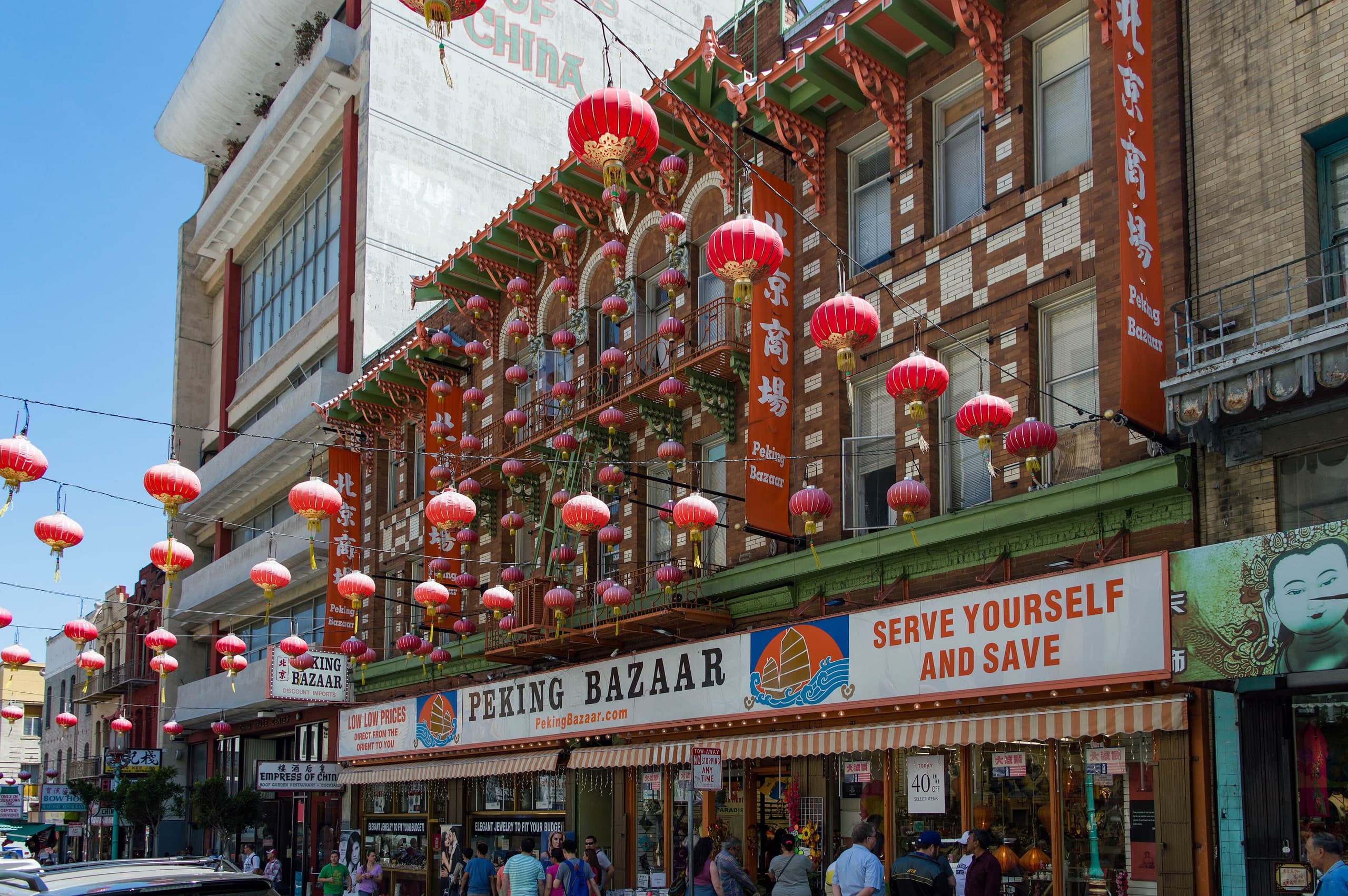 Red lanterns over Grant Avenue in San Francisco Chinatown, with Peking Bazaar storefront and green pagoda eaves