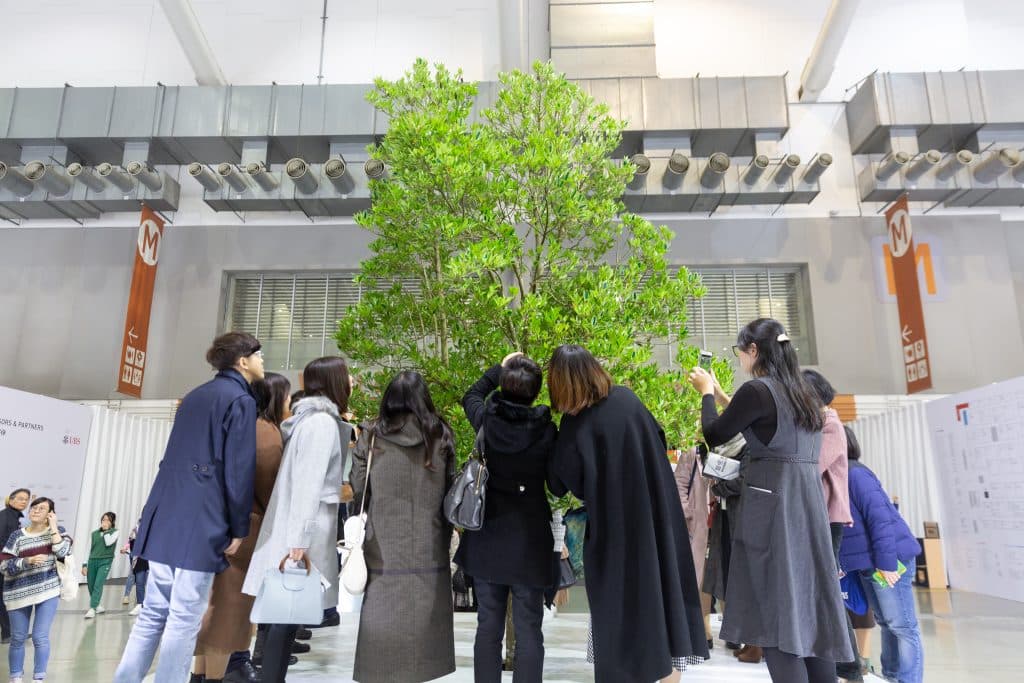 Visitors gathered around a tree installation at Taipei Dangdai with the fair logo and UBS sponsorship visible