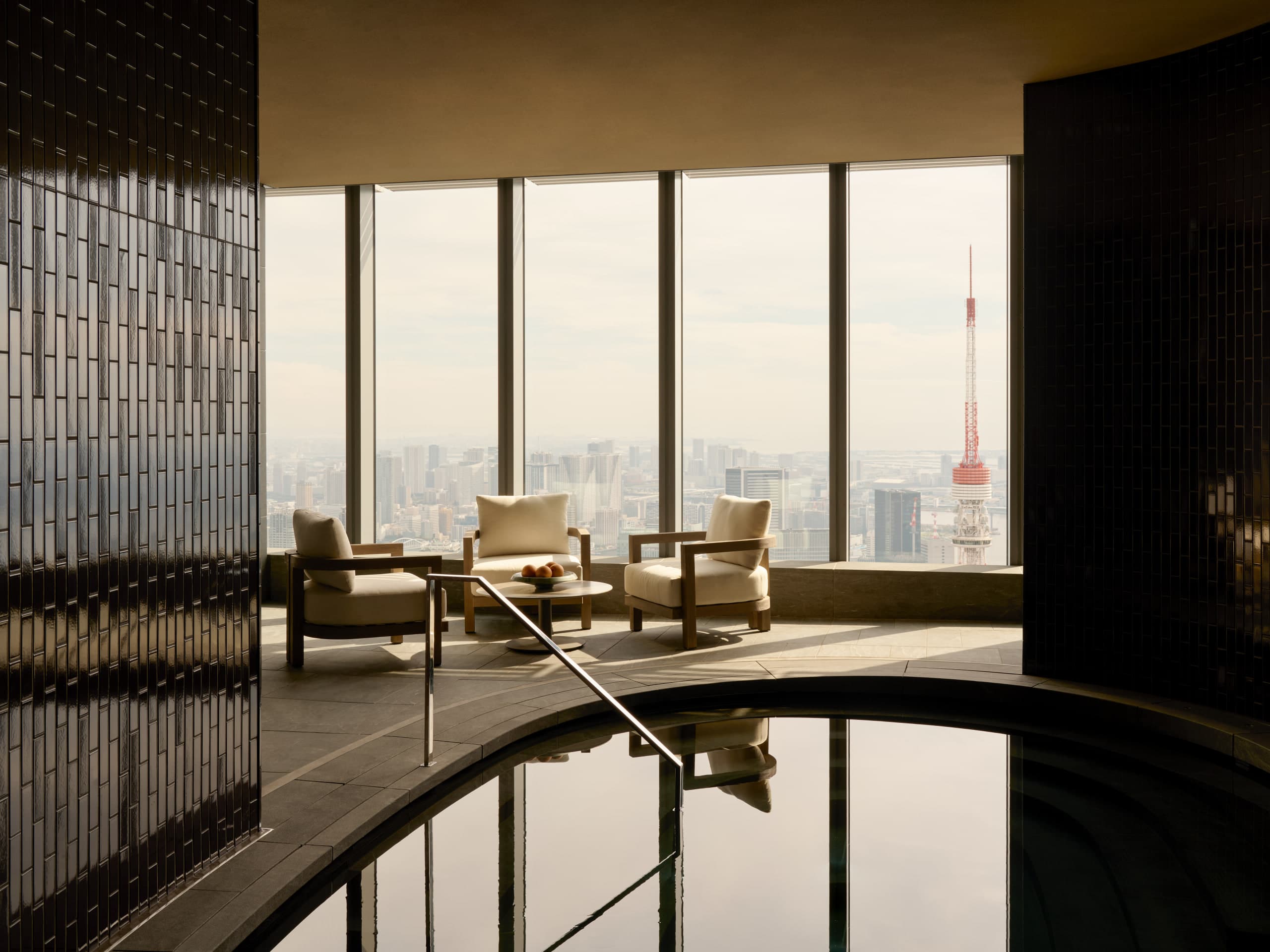 Spa jacuzzi and lounge chairs at Aman Residences Tokyo with Tokyo Tower visible through floor-to-ceiling windows