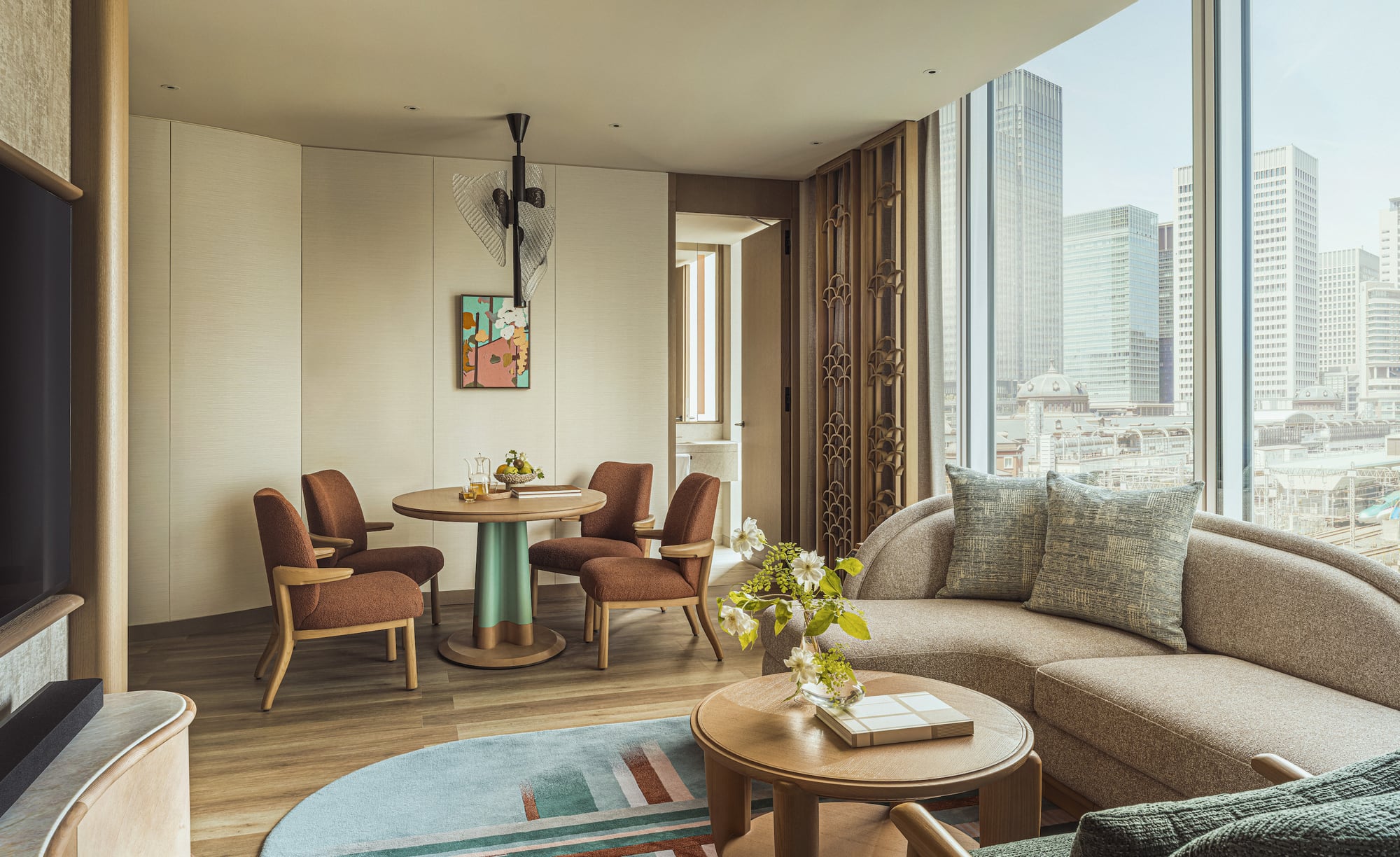 Suite living and dining room with teal pedestal table and Tokyo Station in the window