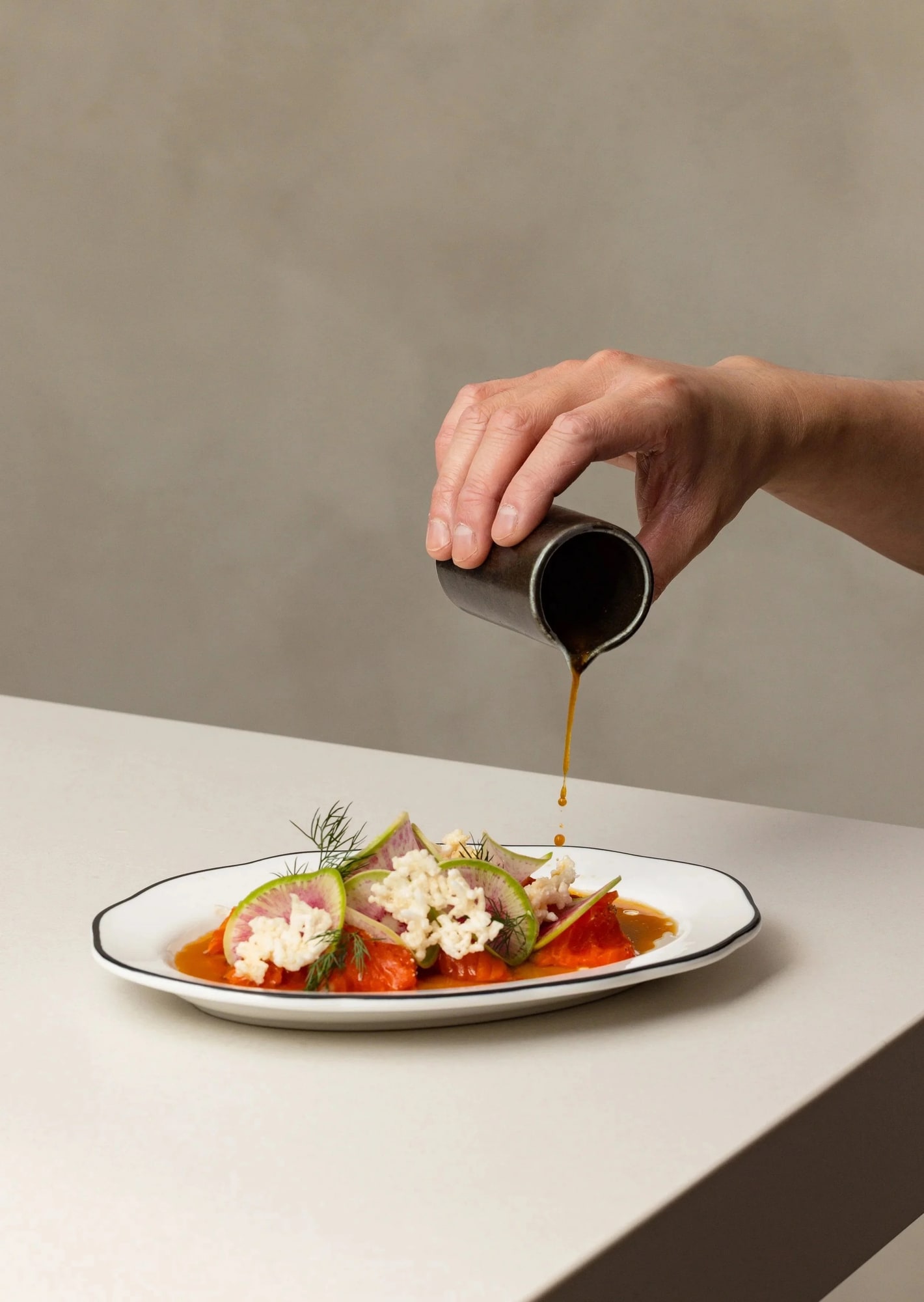 Sauce pour over a plated course at Touk Vancouver