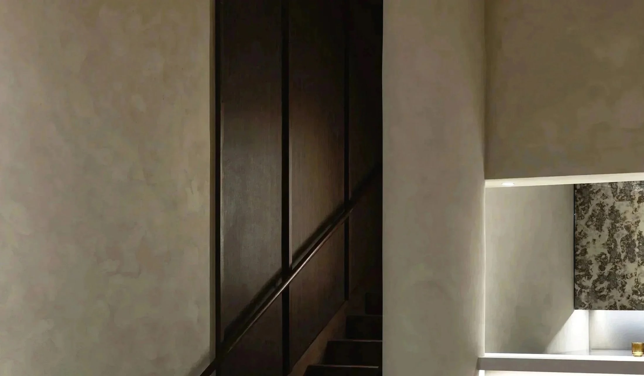 Dark wood stair and lit service niche at Touk in Vancouver