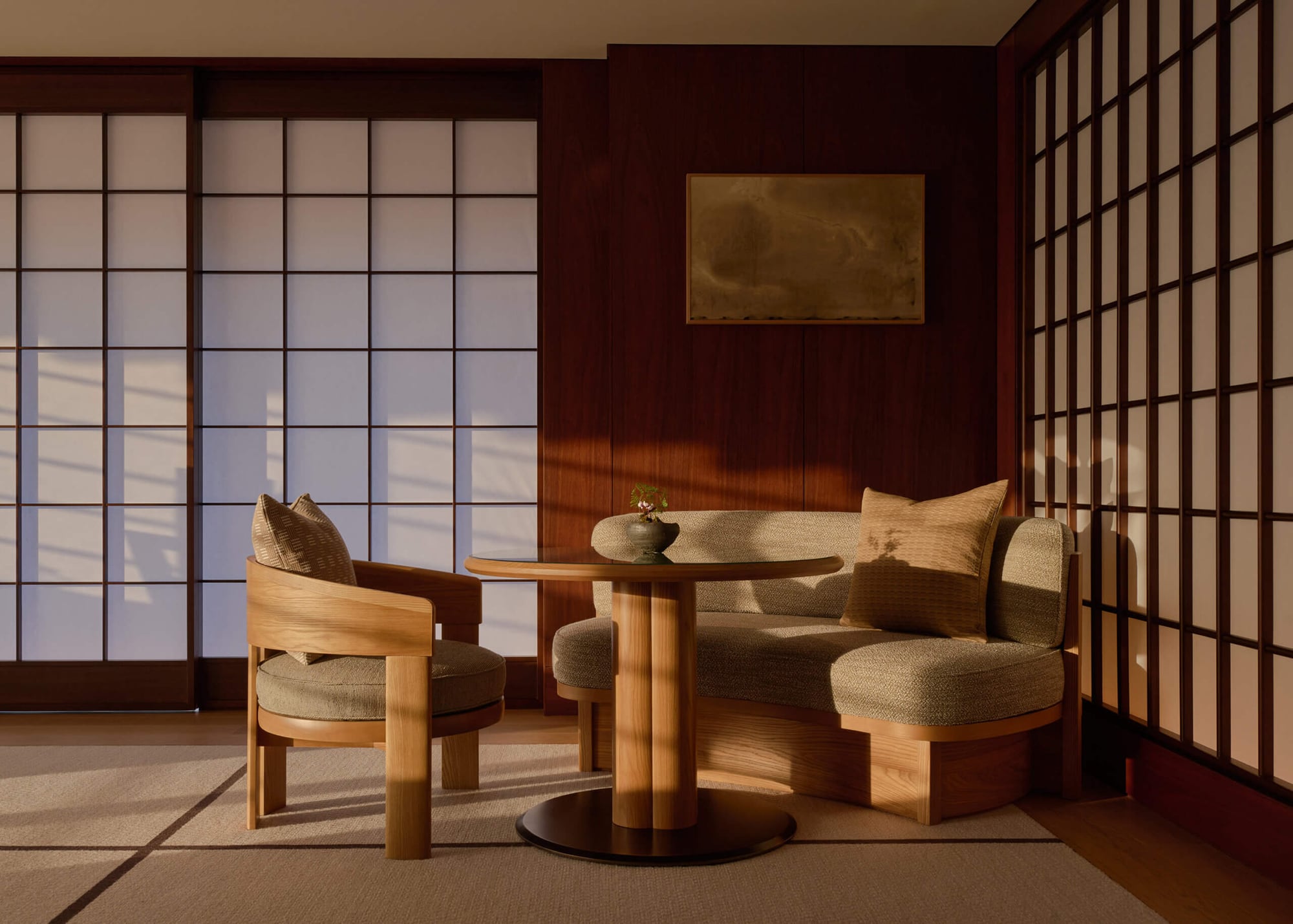 Capella Kyoto suite lounge with shoji screens, low curved seating, and warm late light across wood paneling