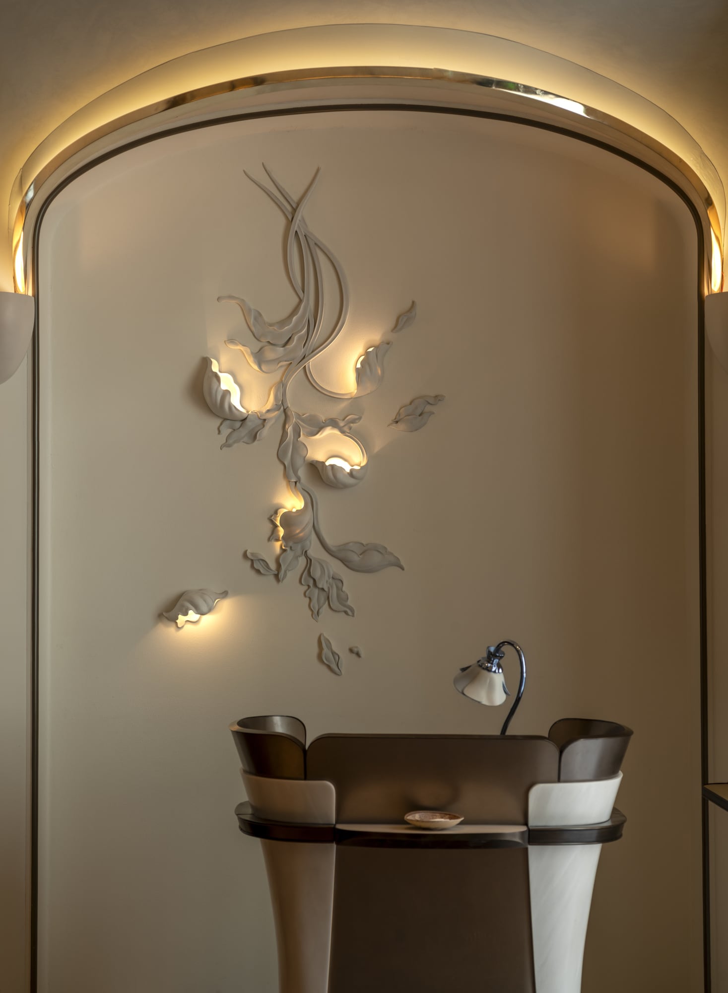 Tate reception desk before an illuminated botanical ceramic wall