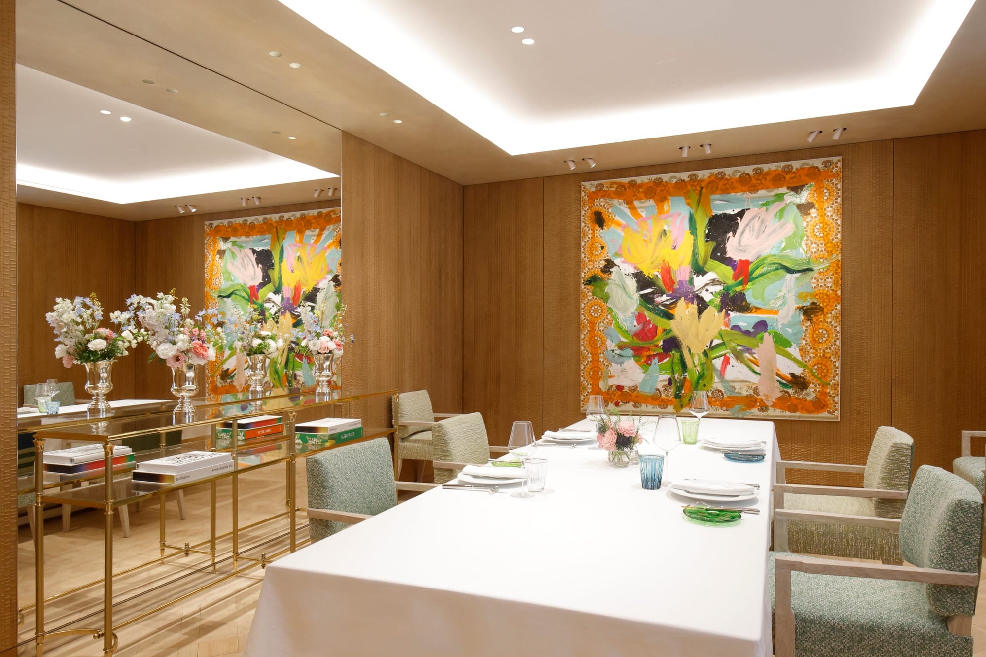 A long white table in a wood-paneled private dining room with a large floral painting