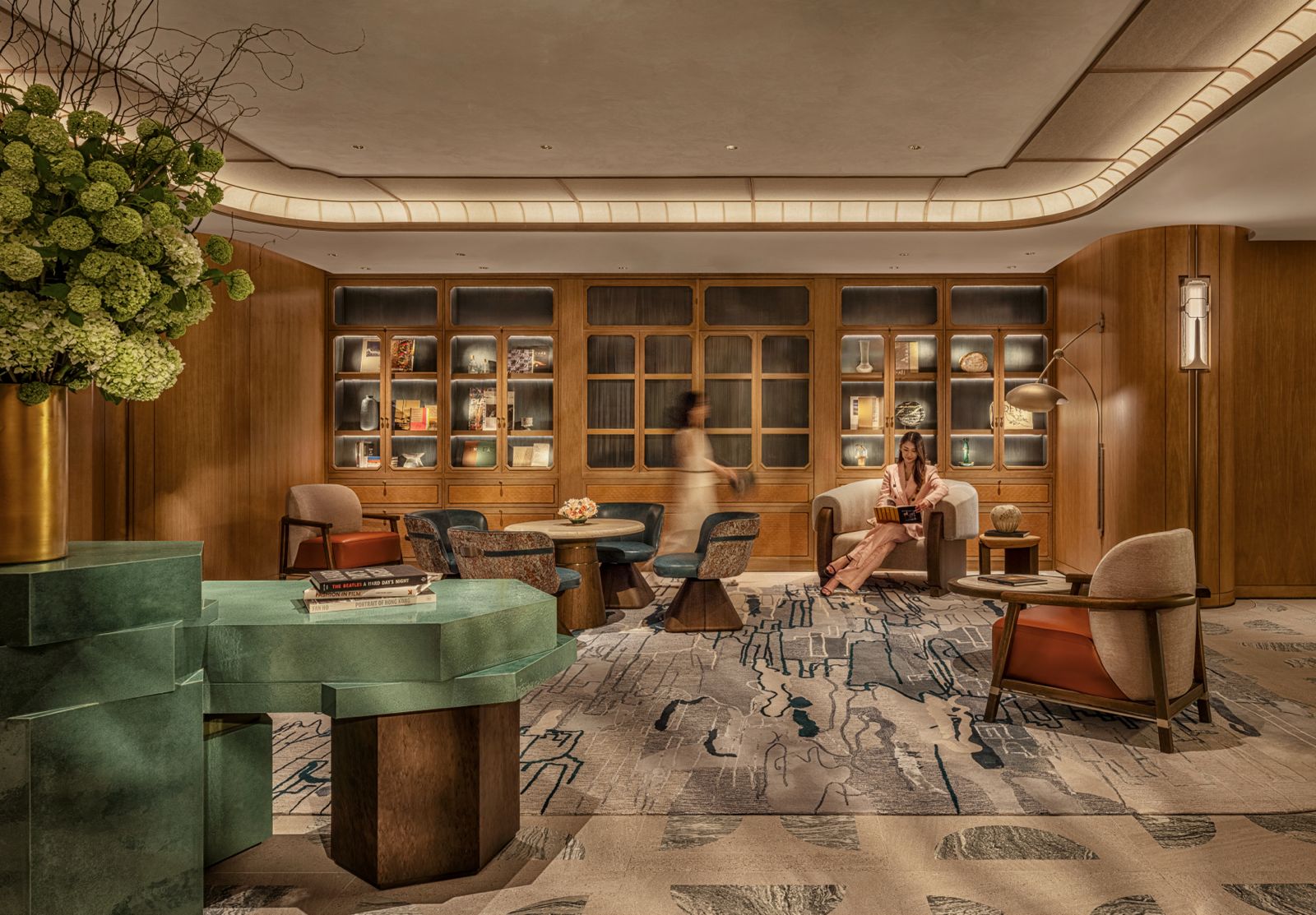 Wood-lined lobby lounge at Mandarin Oriental The Landmark with lit shelving, green stone counter, and residential seating