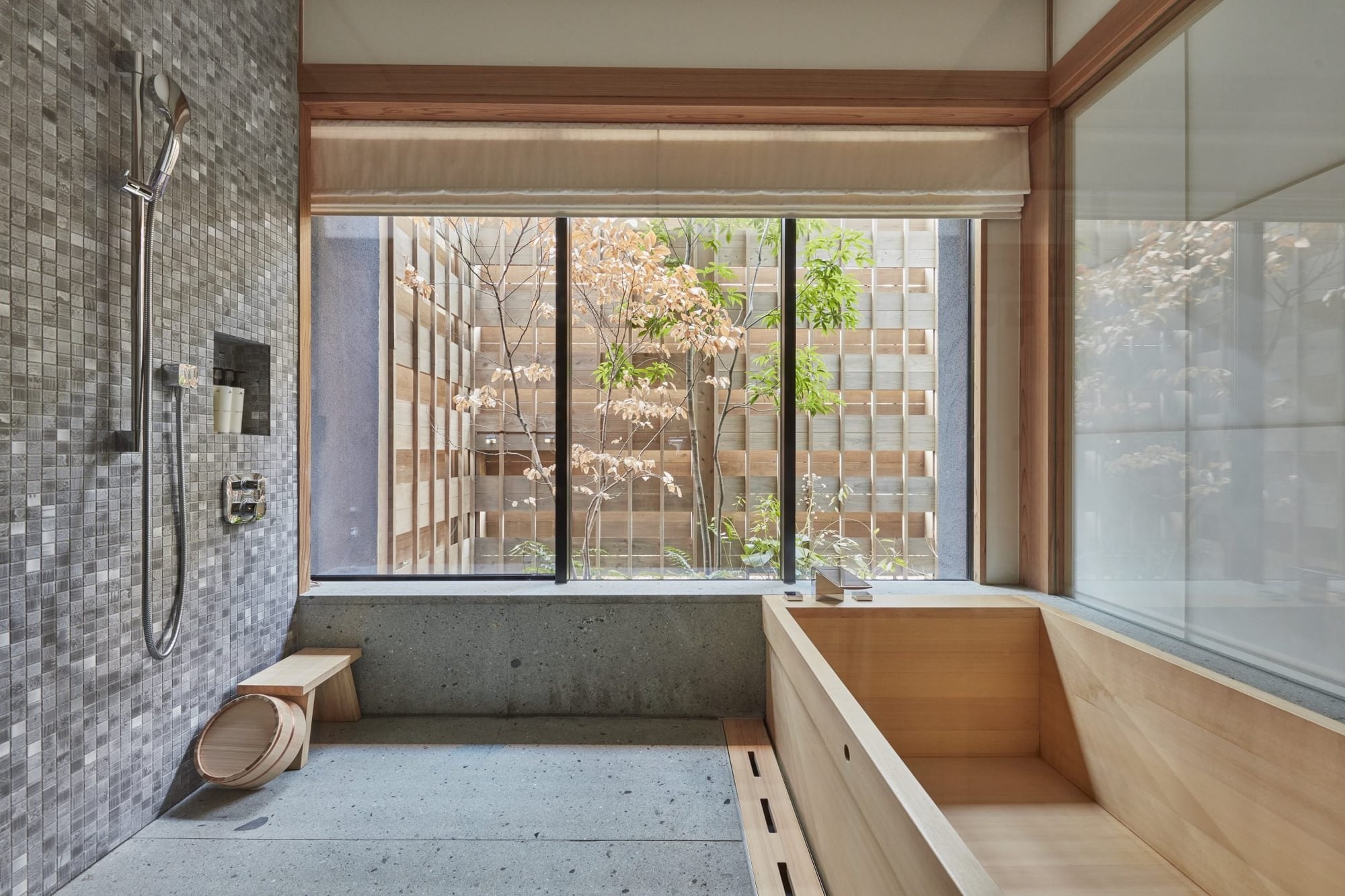 Hinoki soaking tub and granite wet room in a Niwa guest room at Azumi Setoda, looking onto a private garden fence