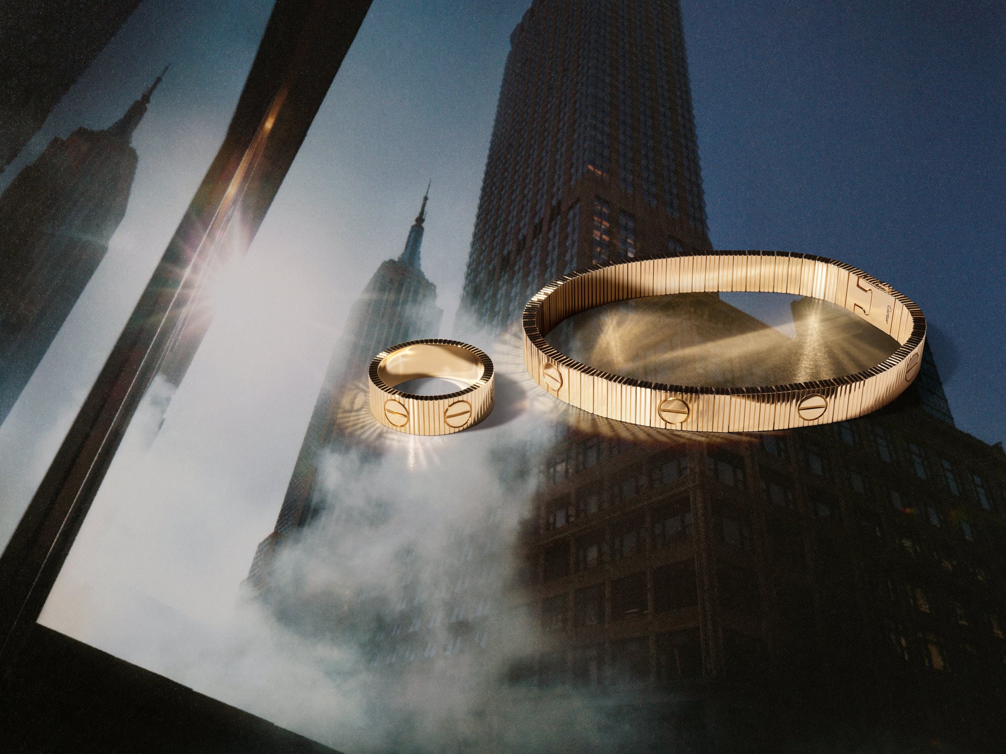 Cartier LOVE Unlimited yellow gold bracelet and ring with fluted gadroons and signature screws against a New York skyline