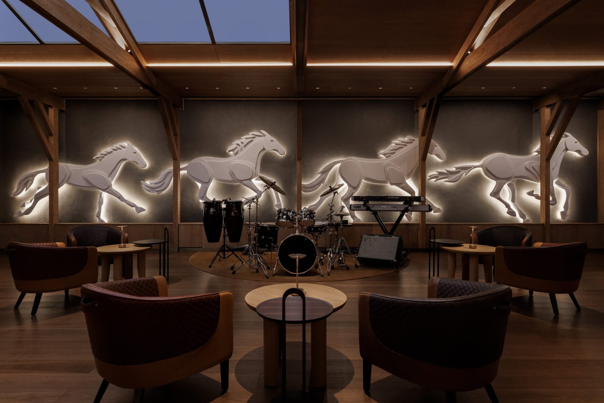 Equestrian lounge at Pony & Plume with backlit galloping-horse reliefs, club chairs, and a live-music stage