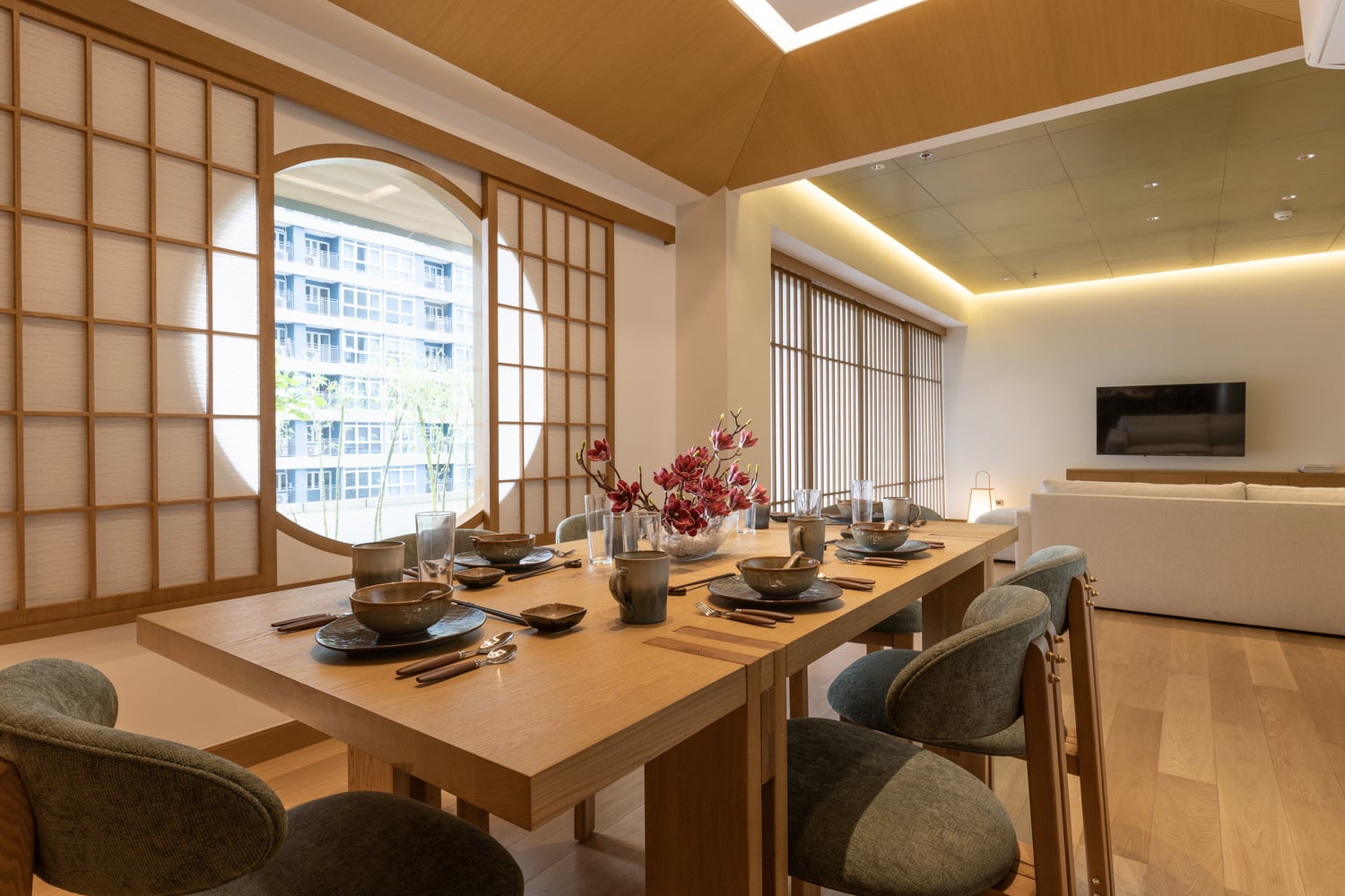 Guest House dining room with a pale oak table, ceramic bowls, shoji screens, and a circular moon window