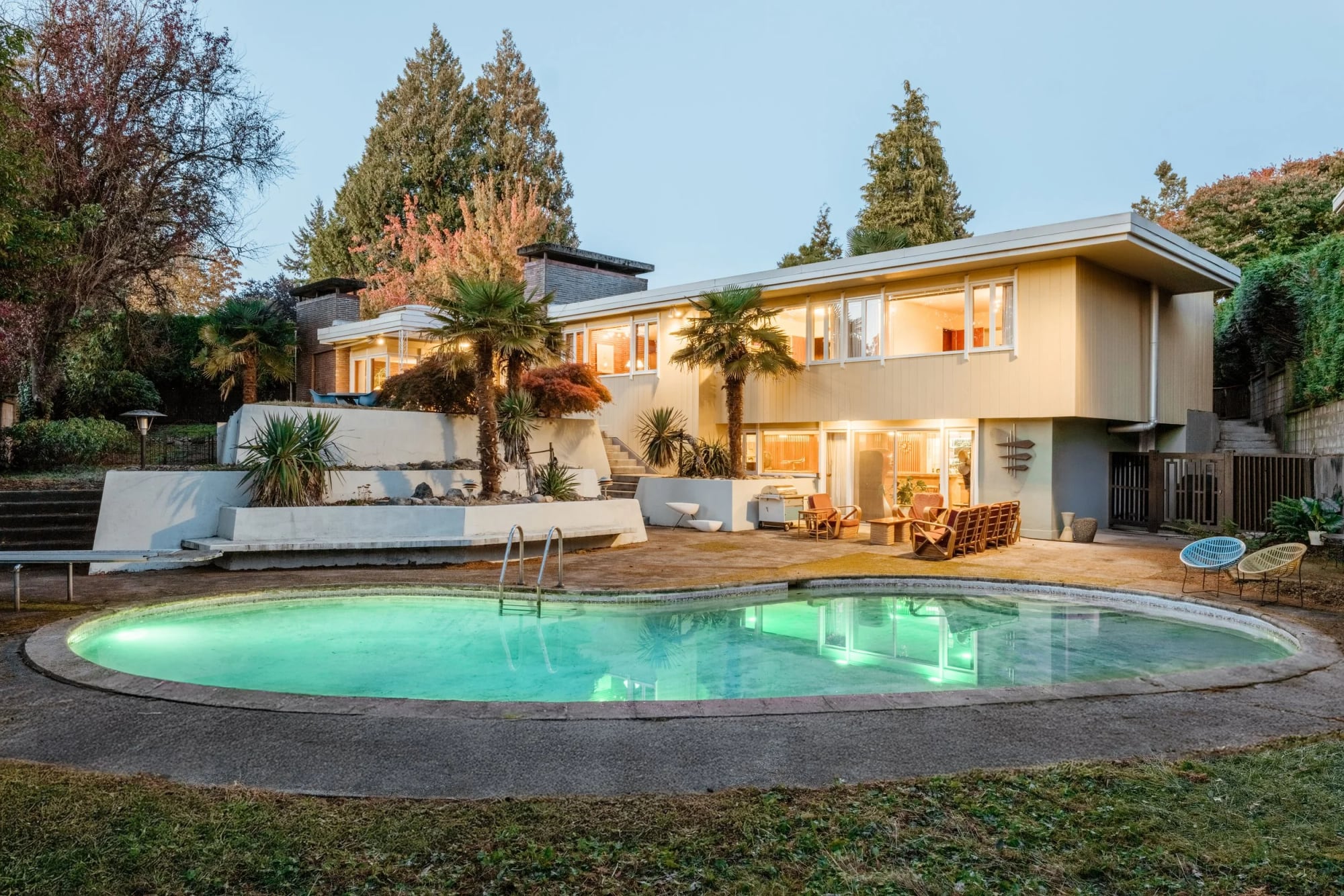 The 1957 Lakeberg Residence at dusk, a low post-and-beam house behind a kidney-shaped pool