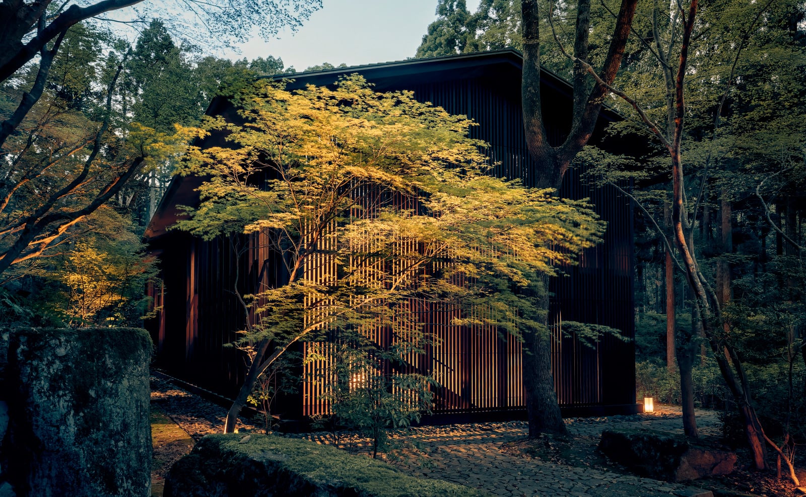 Exterior of an Aman Kyoto Nara guest pavilion with timber lattice and forest hillside beyond